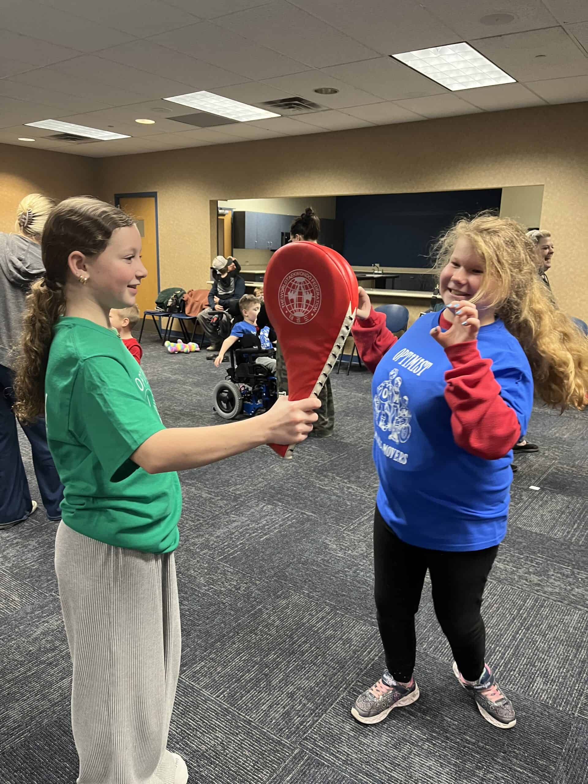 Kids practicing martial arts with focus mitts in a training room.