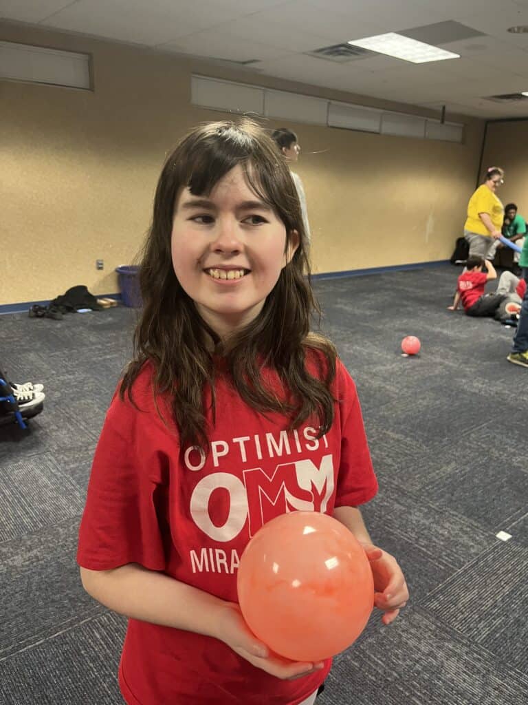 Young girl smiling with a pink ball at a martial arts event.