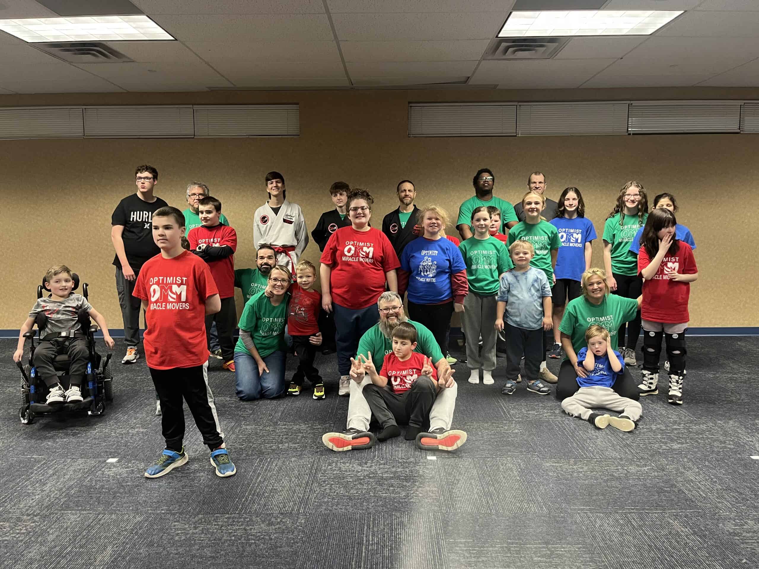 Group of children and adults participating in martial arts training indoors.