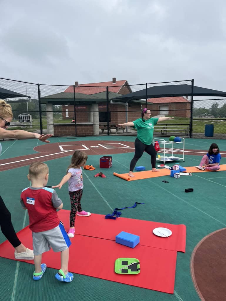 Yoga instructor leading stretching exercises outdoors.