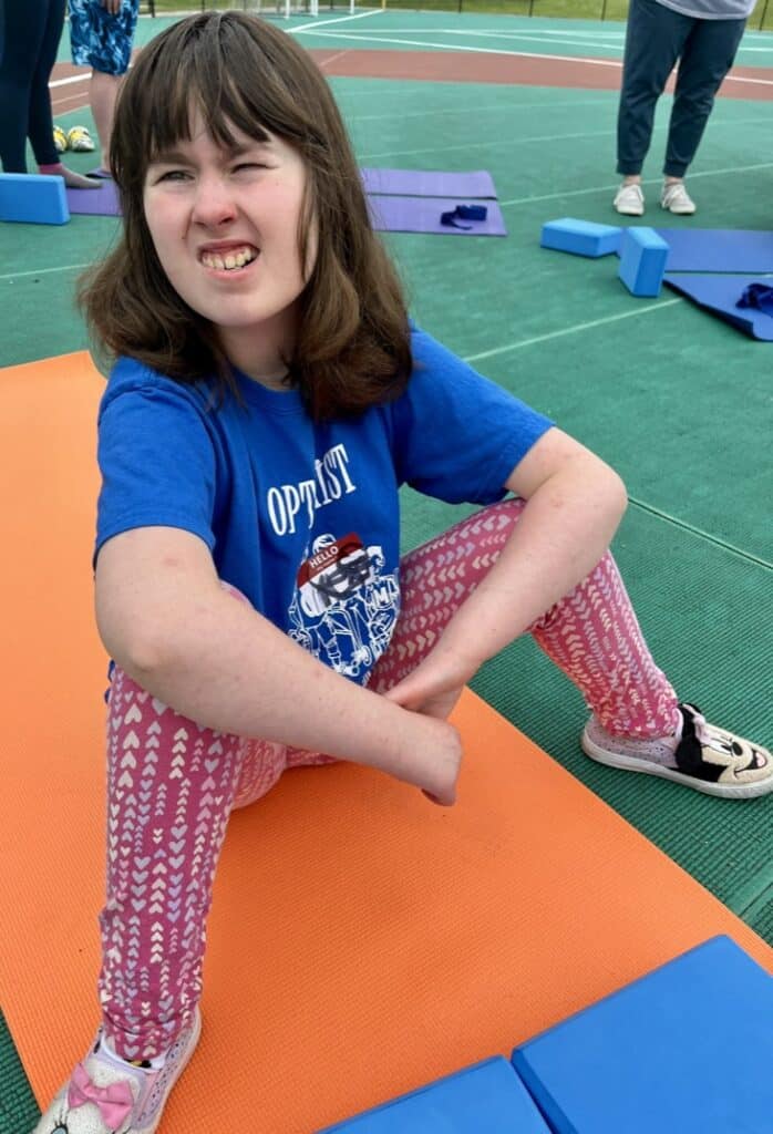 Young girl stretching on yoga mat during outdoor stretching session.